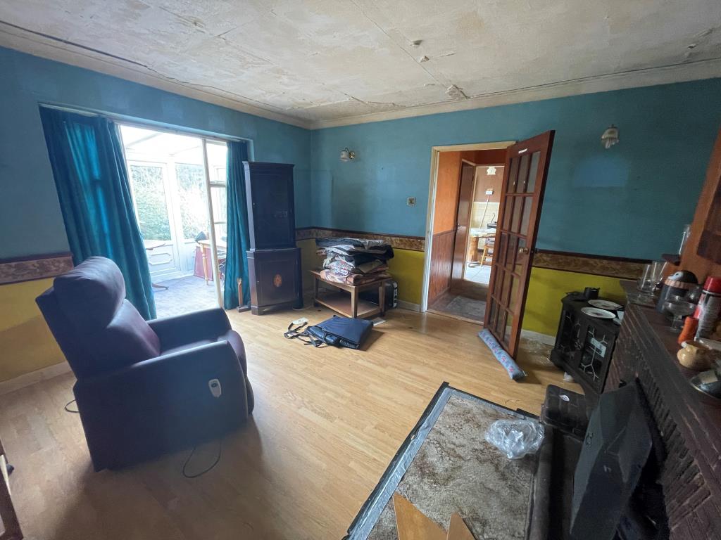 Lot: 60 - THREE-BEDROOM SEMI-DETACHED BUNGALOW - Living room with fireplace looking towards conservatory